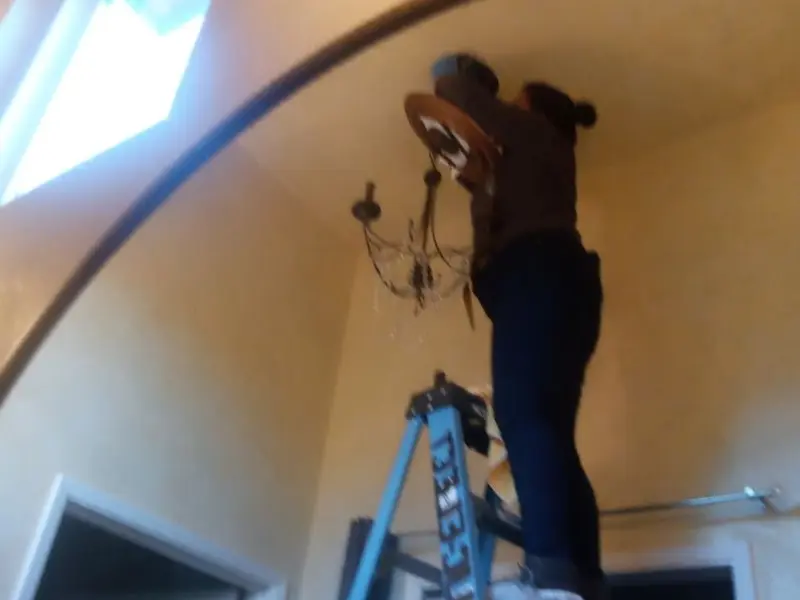 Electrician installing a chandelier in a Joshua residence